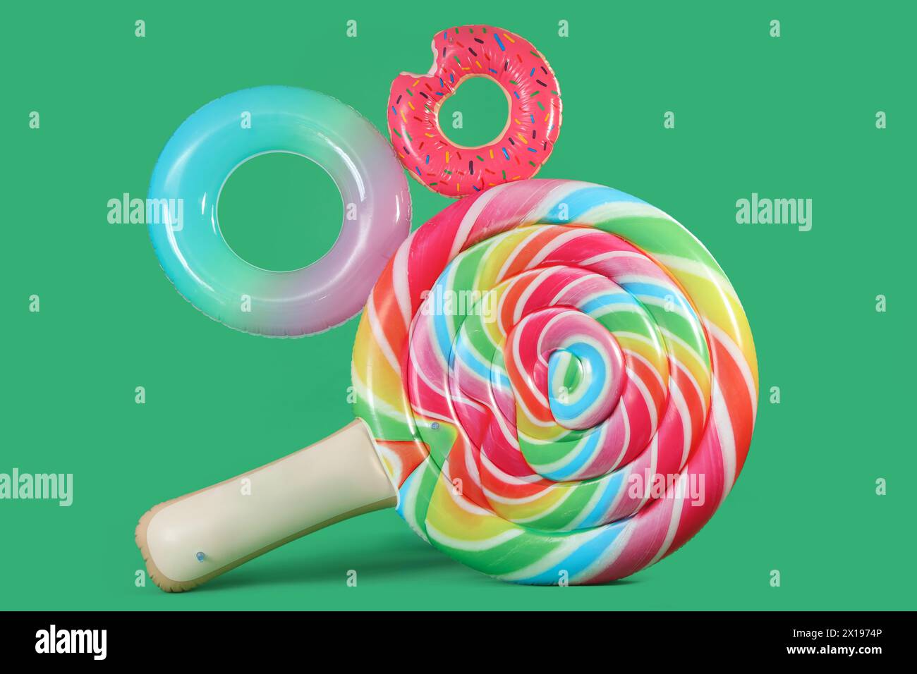 Inflatable rings and swimming mattress in shape of candy on green background Stock Photo