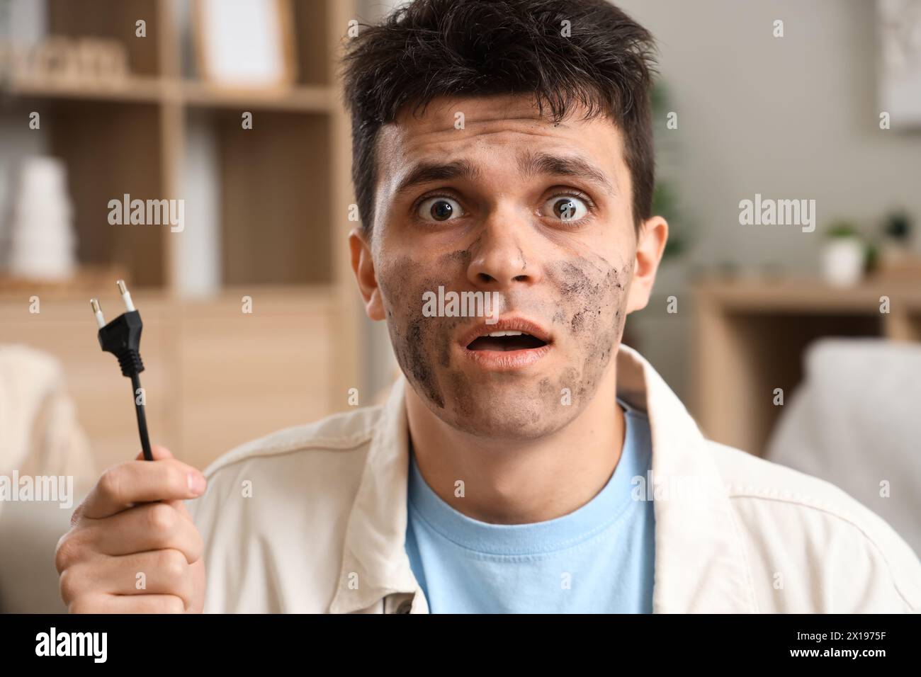 Electrocuted man with burnt face and plug at home, closeup Stock Photo