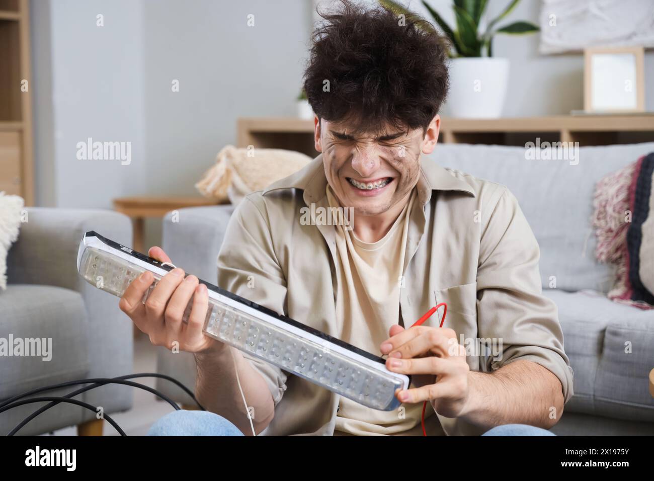 Electrocuted young man with burn face repairing lamp at home Stock ...
