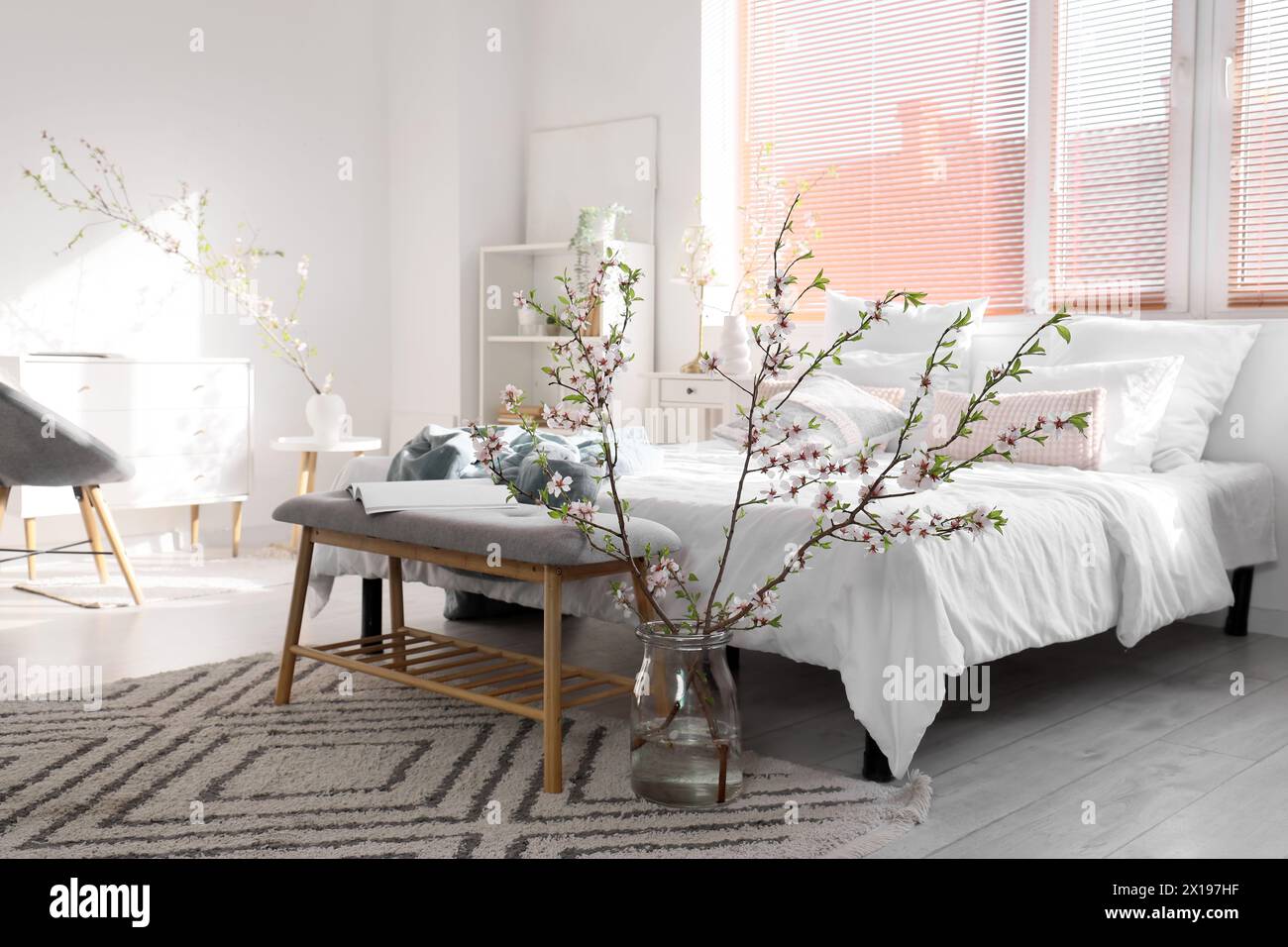 Vase with blooming branches on floor in interior of light bedroom Stock Photo