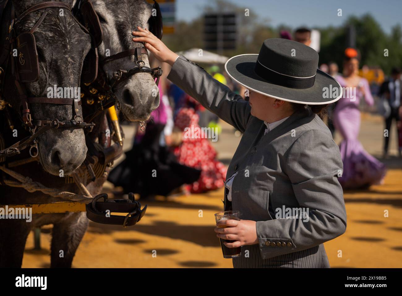 A woman taking care of the horses is seen at the fair. The April Fair is one of the most international and popular festivals in Seville. Created in 1847 as a livestock fair, over time the festive aspect of the event ended up taking over the commercial part, until it became an essential event for Sevillians. For a week, more than a thousand booths installed in the fairgrounds became the second home of the inhabitants of this city, a space where they can share and have fun in company until the early hours of the morning. While the festival lasts, people dressed in typical Andalusian costumes: me Stock Photo