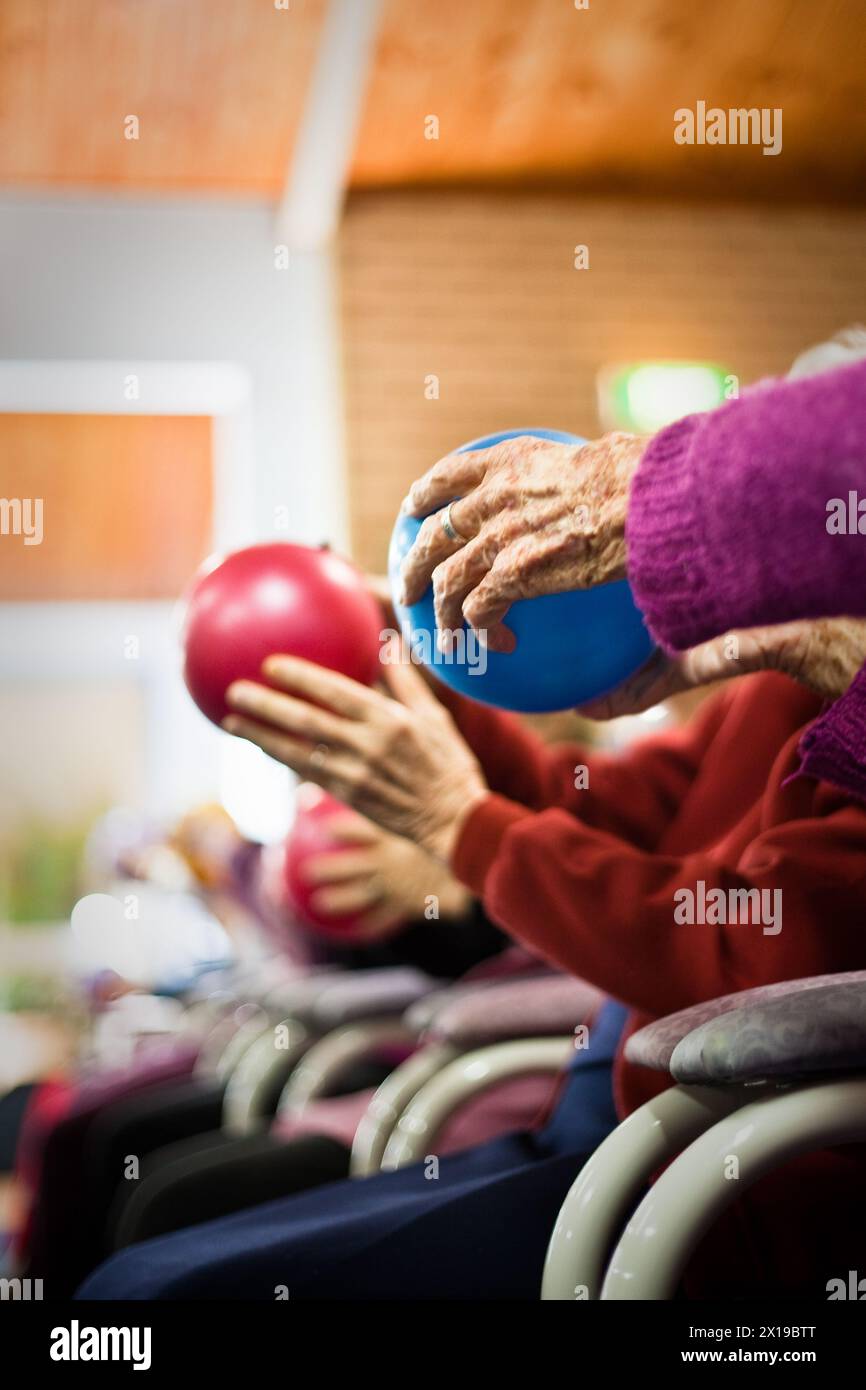 ELDERLY RESIDENTS EXERCISING USING COLOURED BALLS IN AN AGED CARE FACILITY IN AUSTRALIA.. Stock Photo