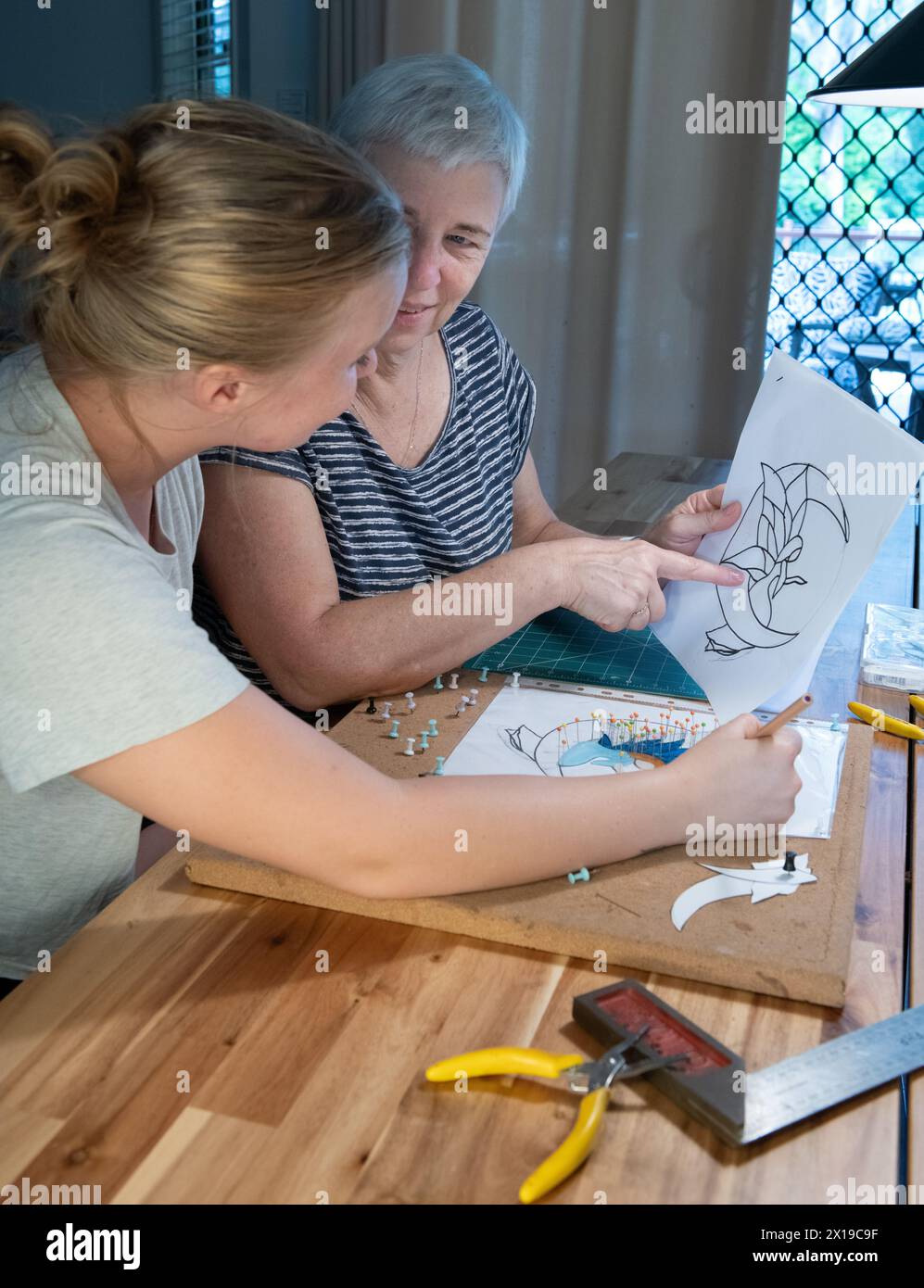 Two ladies working together on a stained glass design Stock Photo