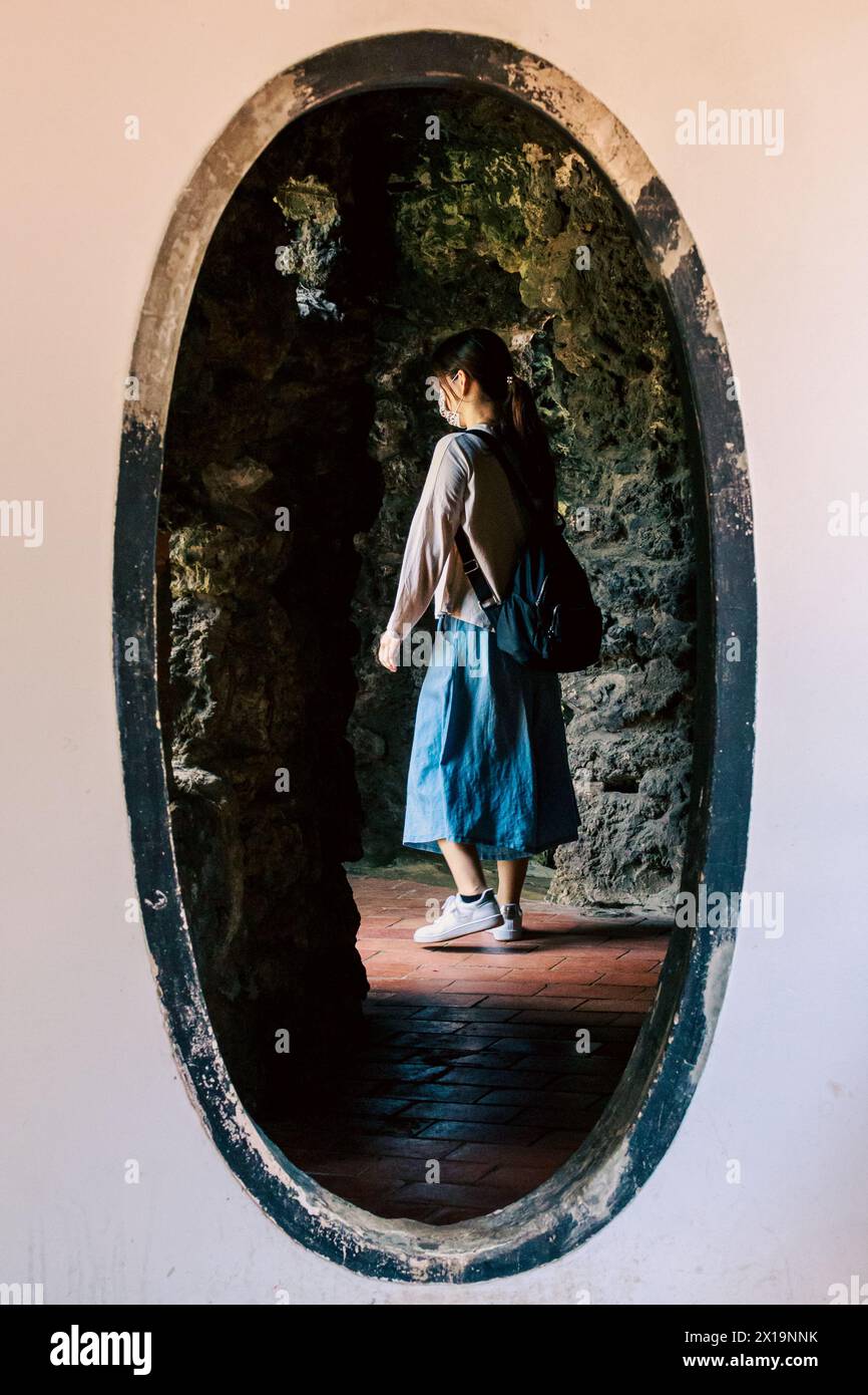 A young female visitor walks through an egg-shaped gate in the Lin Ben Yuan's Family Garden at Banqiao District, New Taipei City, Taiwan. Stock Photo