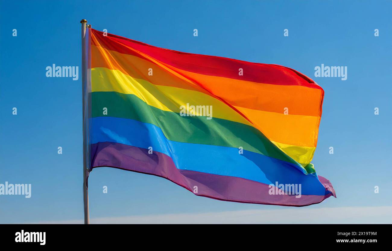 Die Regenbogenfahne flattert im Wind, isoliert, gegen den blauen Himmel, mit einer solchen Fahne wird in zahlreichen Kulturen weltweit die Stimmung fü Stock Photo