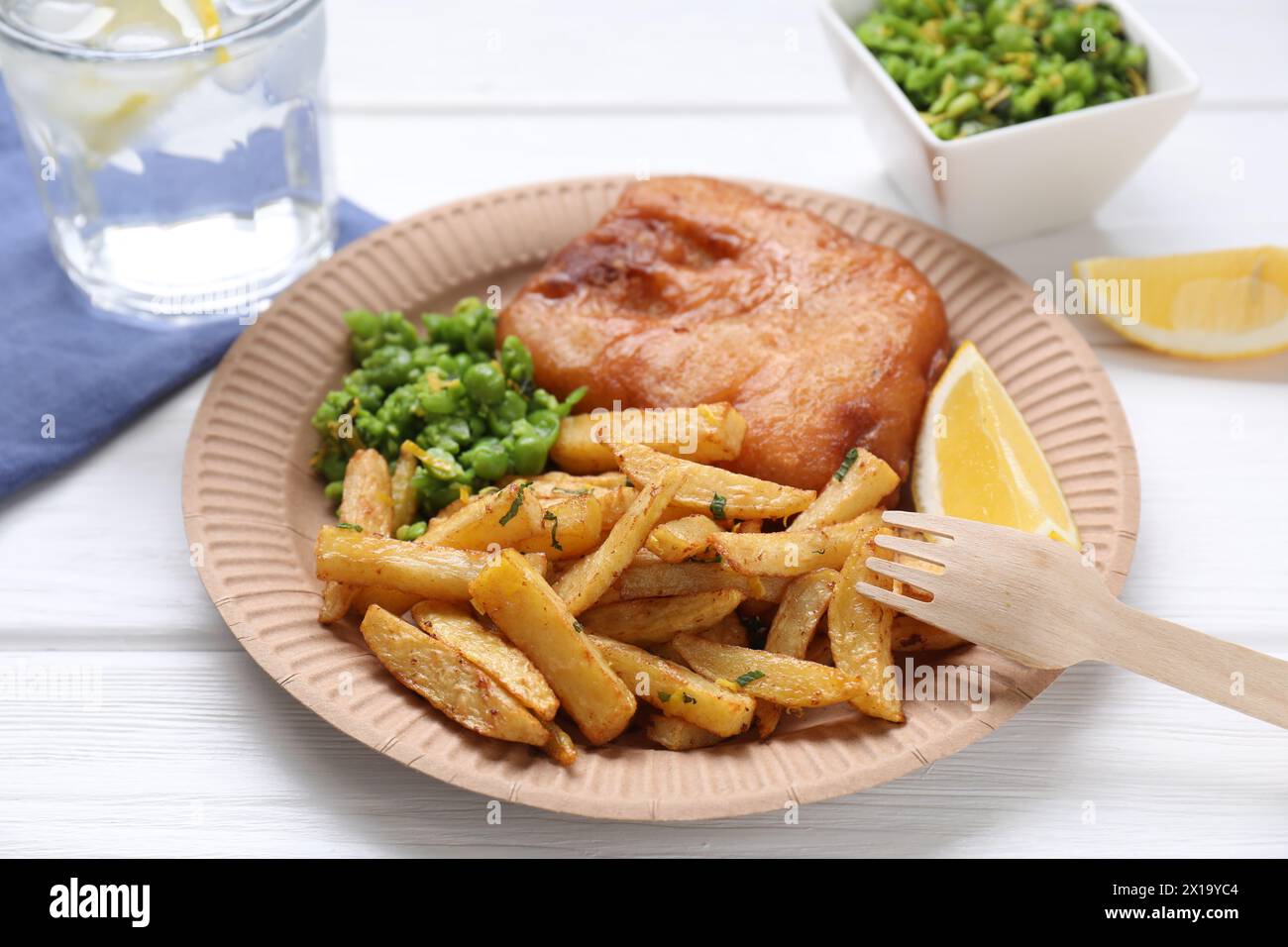 Tasty fish, chips, peas and lemon on white wooden table, closeup Stock Photo