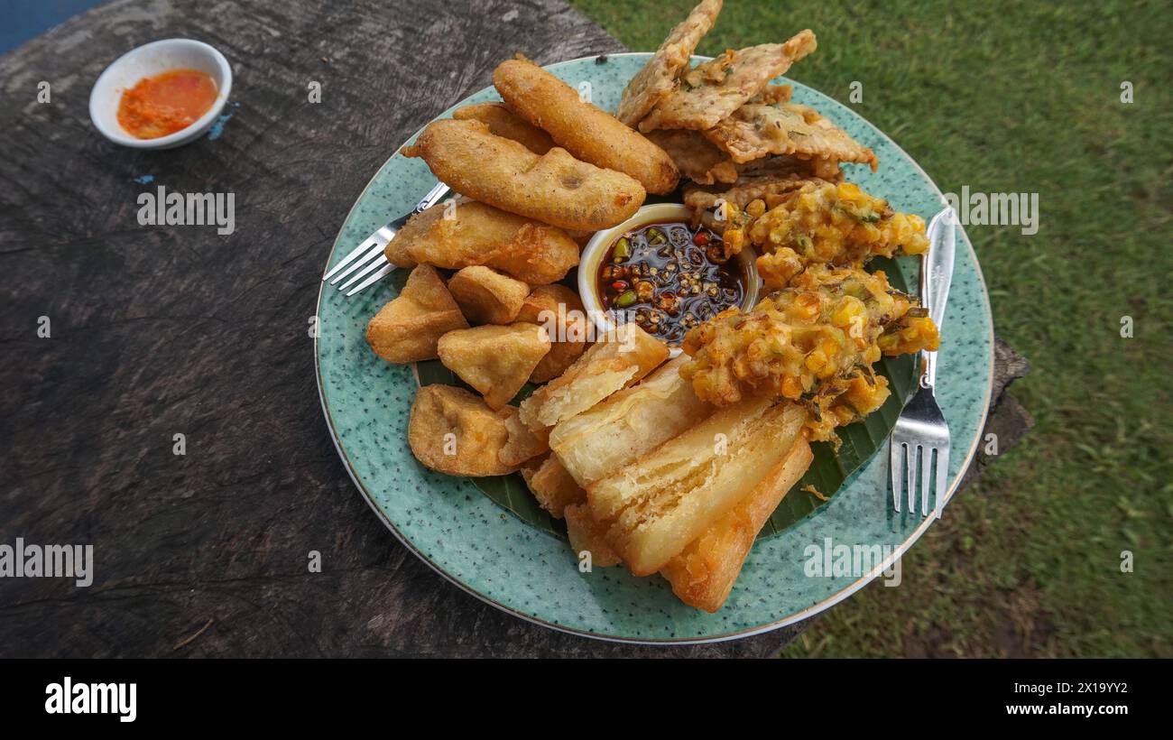 various fried foods served on plates that are famous in Indonesia, such as corn bakwan, mendoan, fried banana, fried cassava and fried tofu Stock Photo