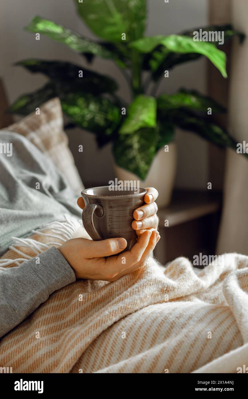 a caucasian man relaxing at home, drinking coffee in bed under blanket Stock Photo