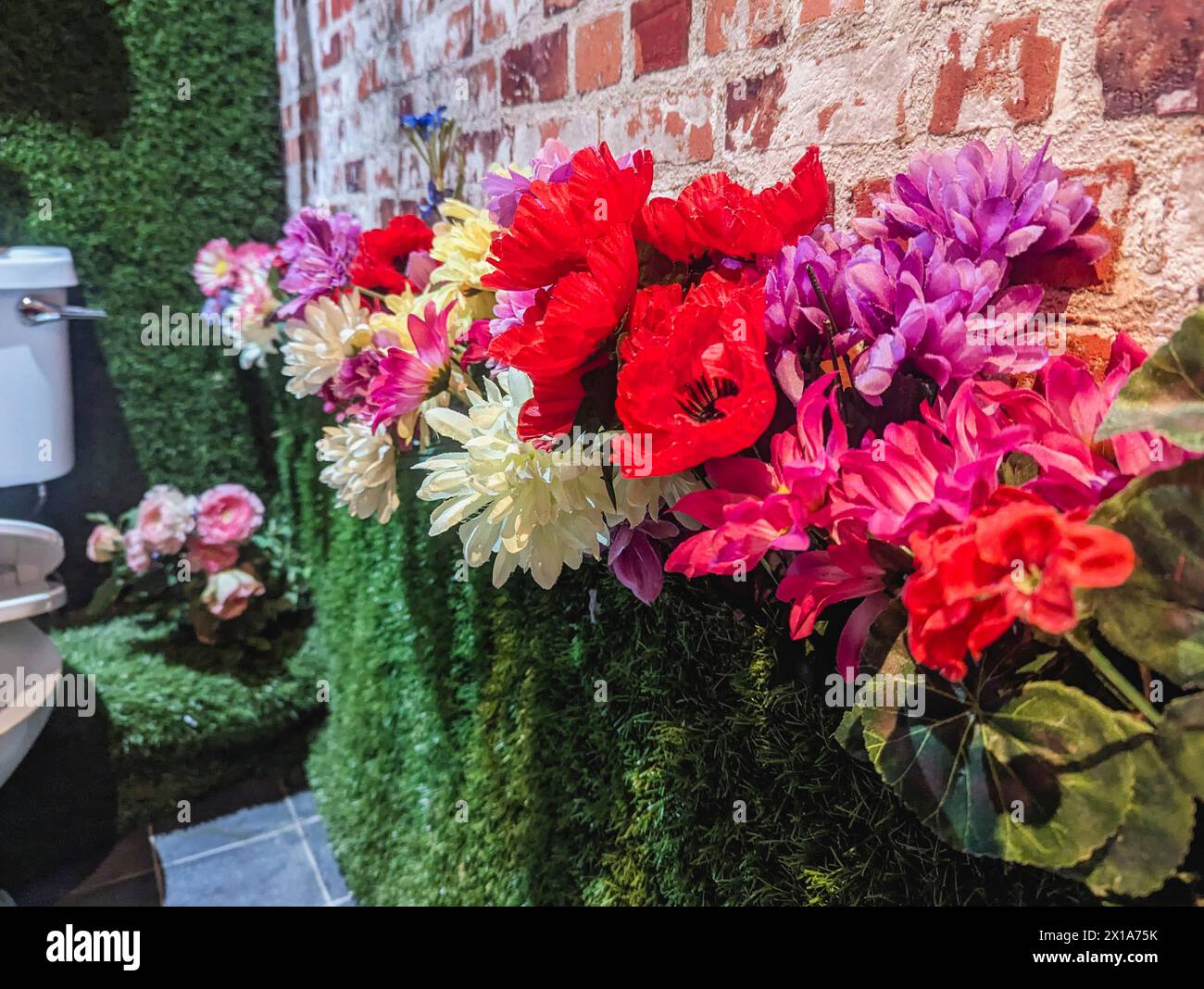 Artificial flowers and grass on the walls of the public toilet in a cafe, Northern Ireland. Stock Photo