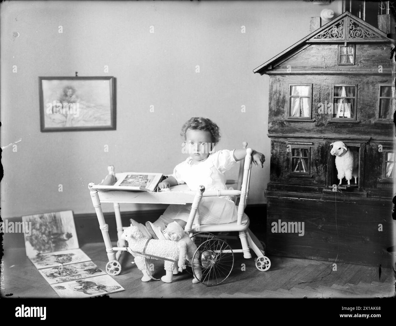 Infant in the child's armchair, with his toys: a doll's house, a sheep, puppet and picture-book, 1918 - 19180101 PD4015 - Rechteinfo: Rights Managed (RM) Stock Photo