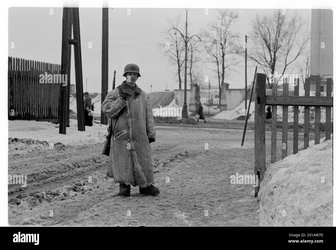 Joe J. Heydecker as guard duty in Warszawa, Joe J. Heydecker in full of winter equipment with long sheepskin coat, wooden boots, helmet and rifle as guard duty on the entrance to the board and lodgings for soldiers in the Wolska street, 1.2.1941 - 19410201 PD0075 - Rechteinfo: Rights Managed (RM) Stock Photo
