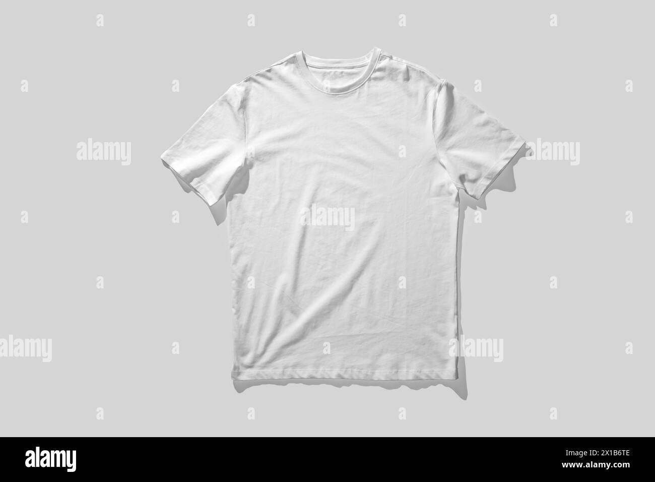 Plain White T-Shirt Laid Flat Against a Solid Gray Background Stock Photo