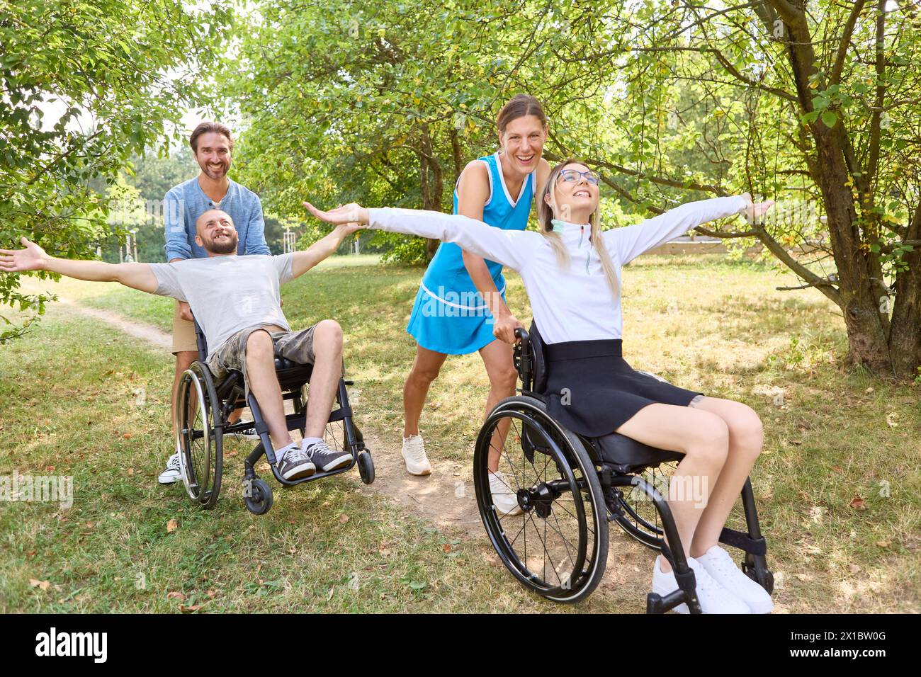 A group of friends, including two people using wheelchairs, enjoy a happy moment outdoors, showcasing diversity and accessibility in a sunny park. Stock Photo