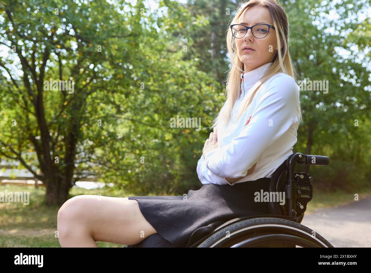 A confident woman who uses a wheelchair is portrayed enjoying a sunny day outdoors, promoting inclusivity and empowerment. Stock Photo