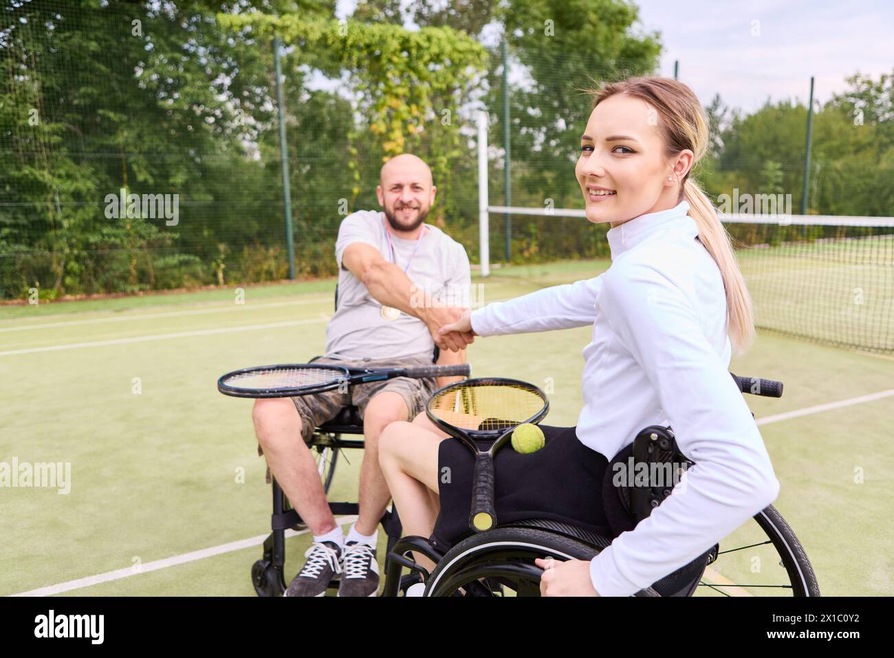 A paraplegic man and woman engaging in wheelchair tennis, showcasing positivity and adaptive sports. Stock Photo