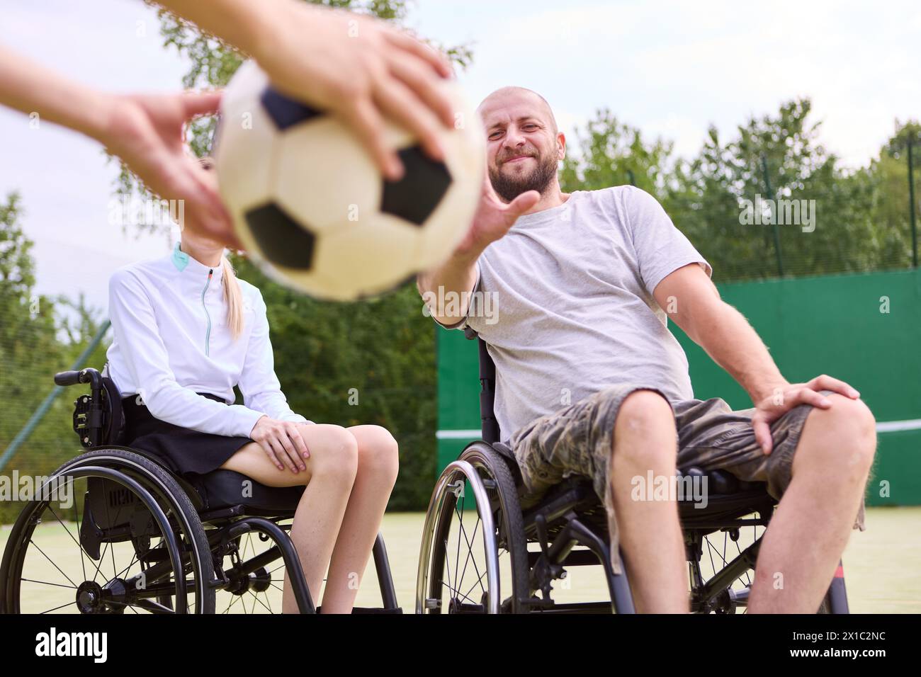 A group of active adults in wheelchairs engaging in a sport outdoors on a sunny day, exemplifying inclusion and teamwork. Stock Photo