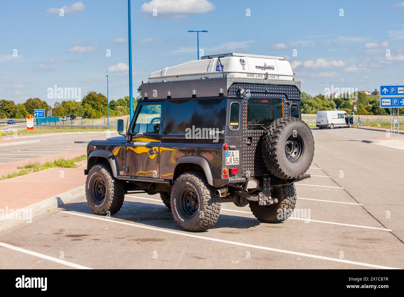 Land Rover Defender with roof rack in parking lot on a clear day. Stock Photo