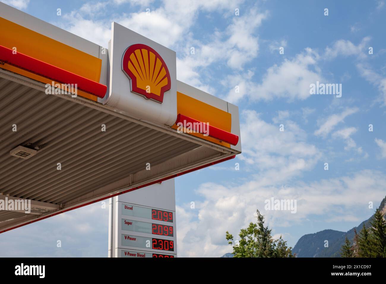 Shell gas station canopy and price board against a cloudy sky in Austria. Stock Photo