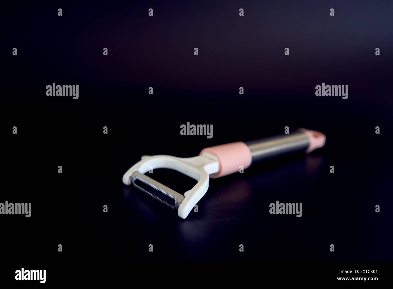a pink vegetable peeler on a black background Stock Photo