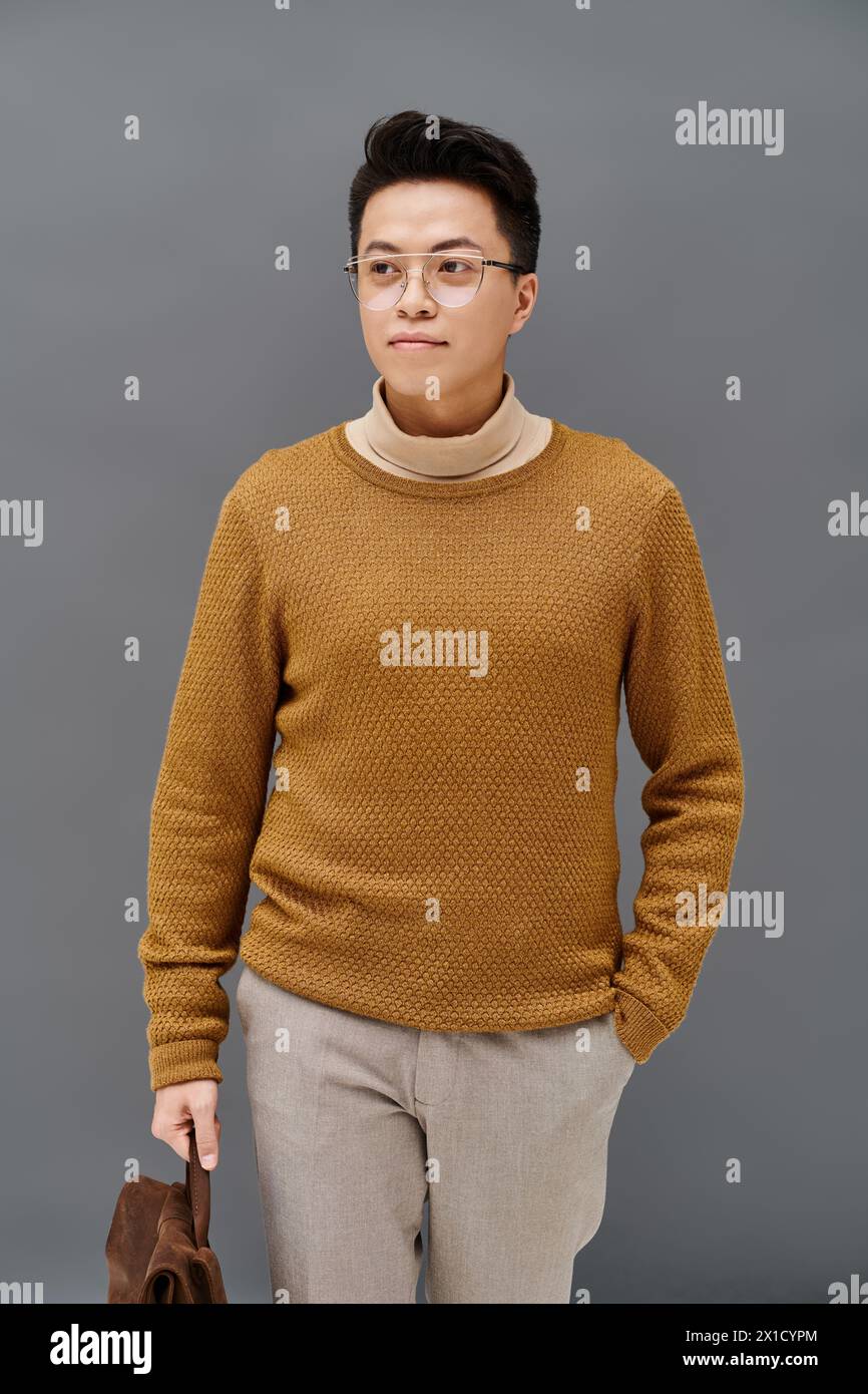 A fashionable young man in a brown sweater and tan pants strikes a dynamic pose. Stock Photo