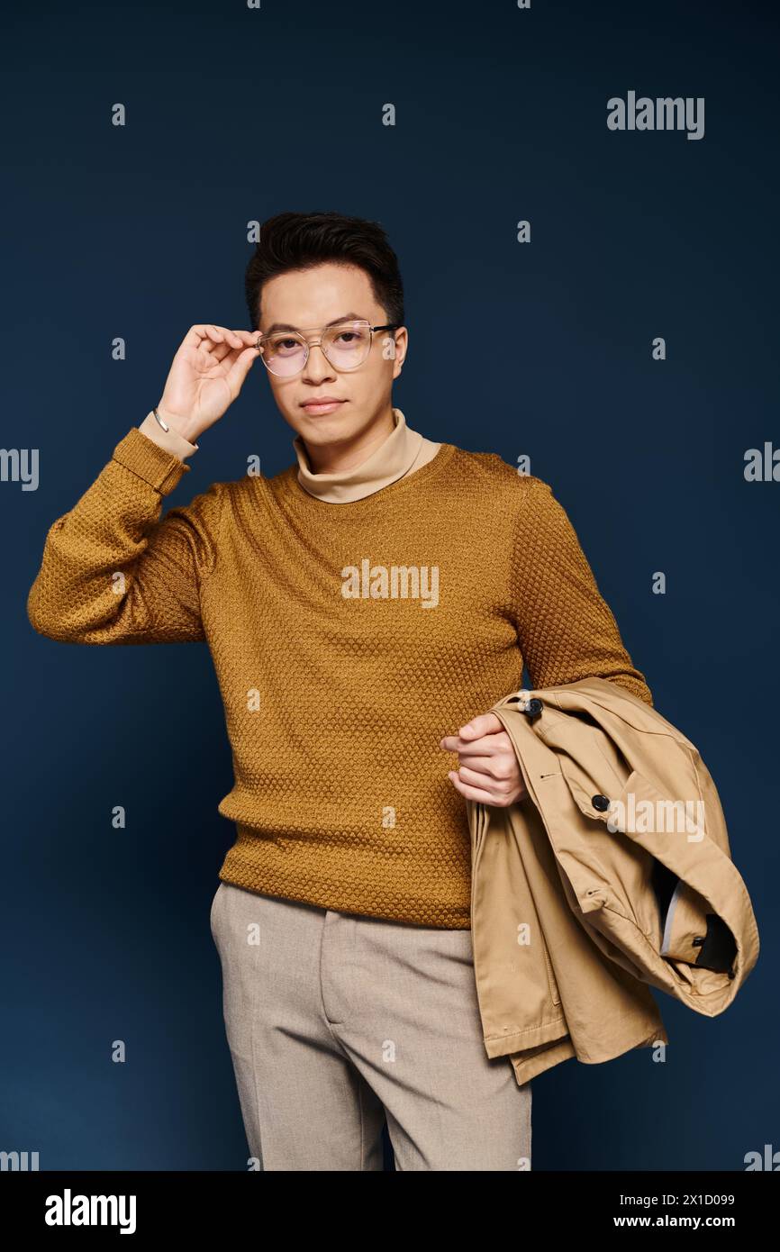 A fashionable young man poses actively in a brown sweater and tan pants, exuding elegance and style. Stock Photo