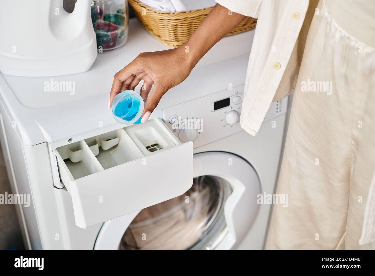 African-American woman cleans a washing machine in a bathroom as part of her housework routine. Stock Photo