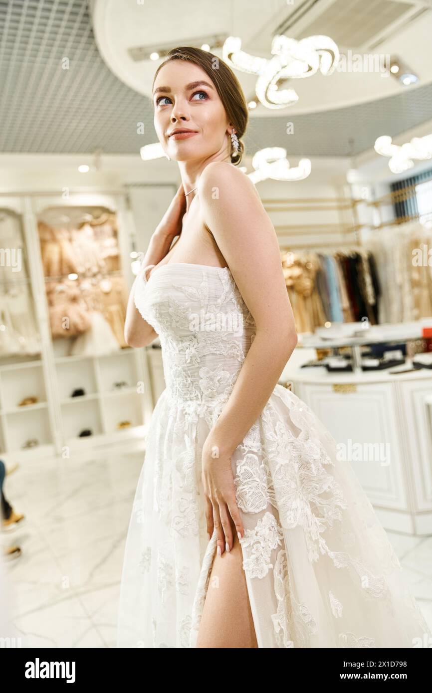 A young brunette bride poses in a white dress, exuding elegance and beauty during a photoshoot in a wedding salon. Stock Photo