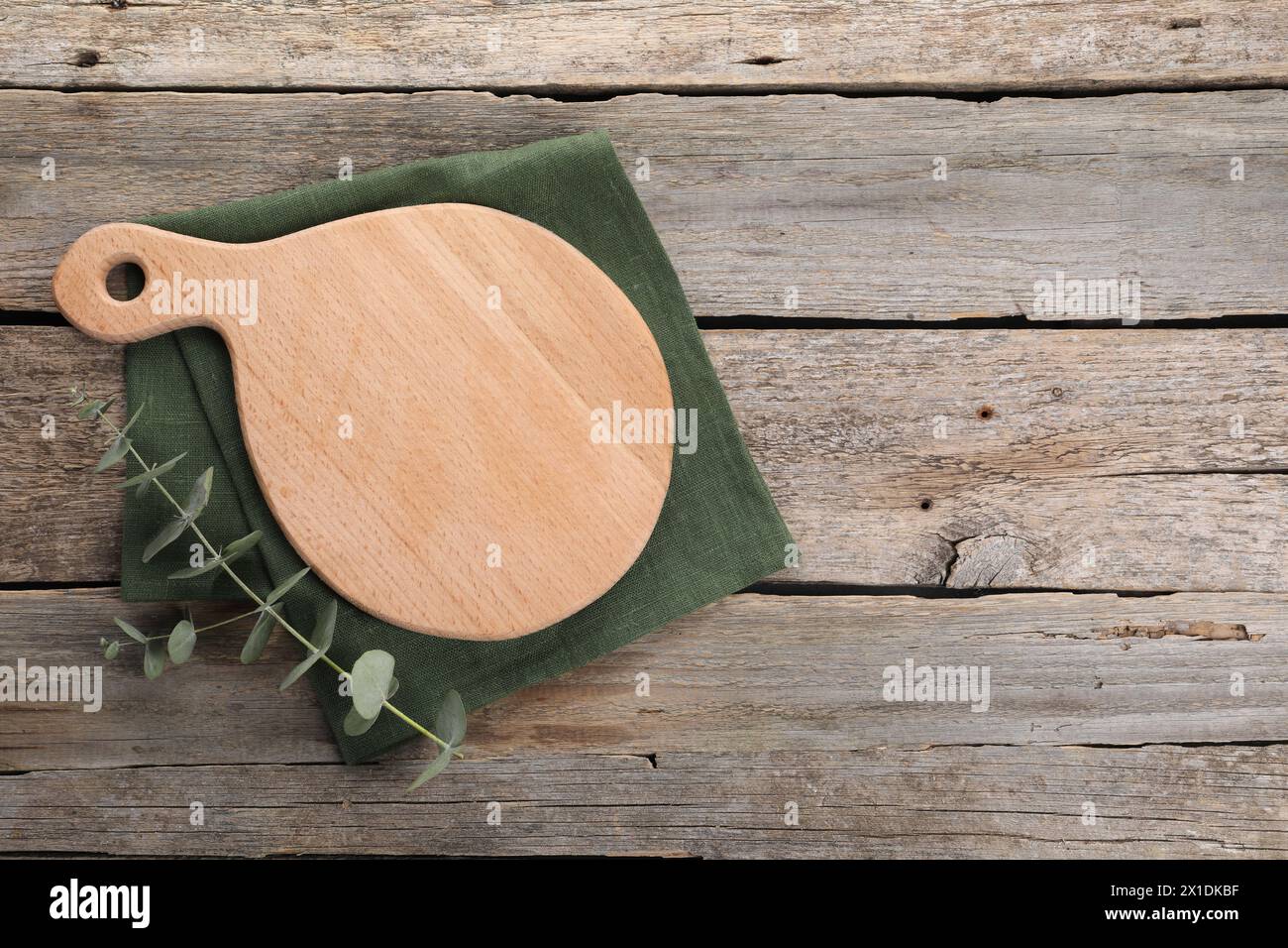 Cutting board, eucalyptus branch and napkin on wooden table, top view. Space for text Stock Photo