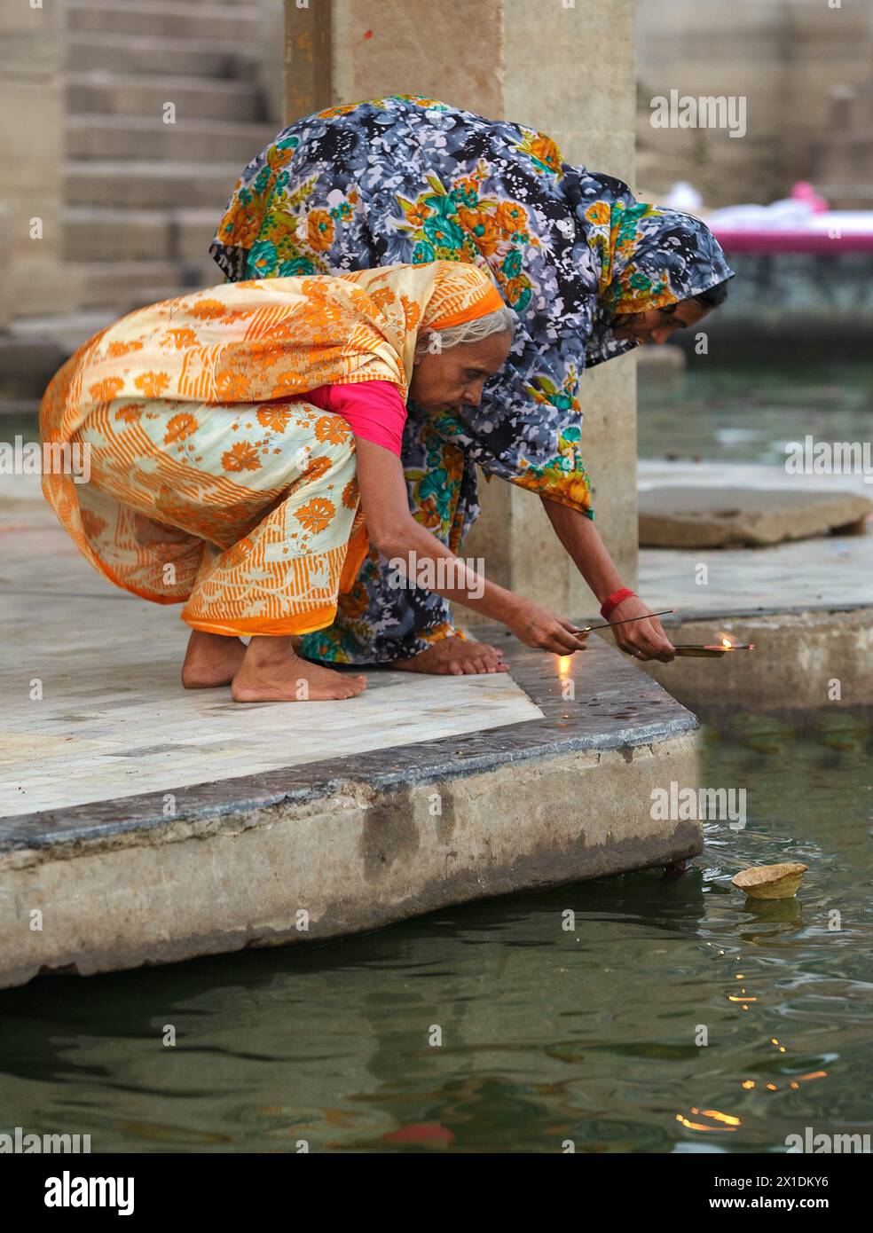 Two pilgrim women worshiping the Ganges River at Varanasi with incense and a flame. Stock Photo