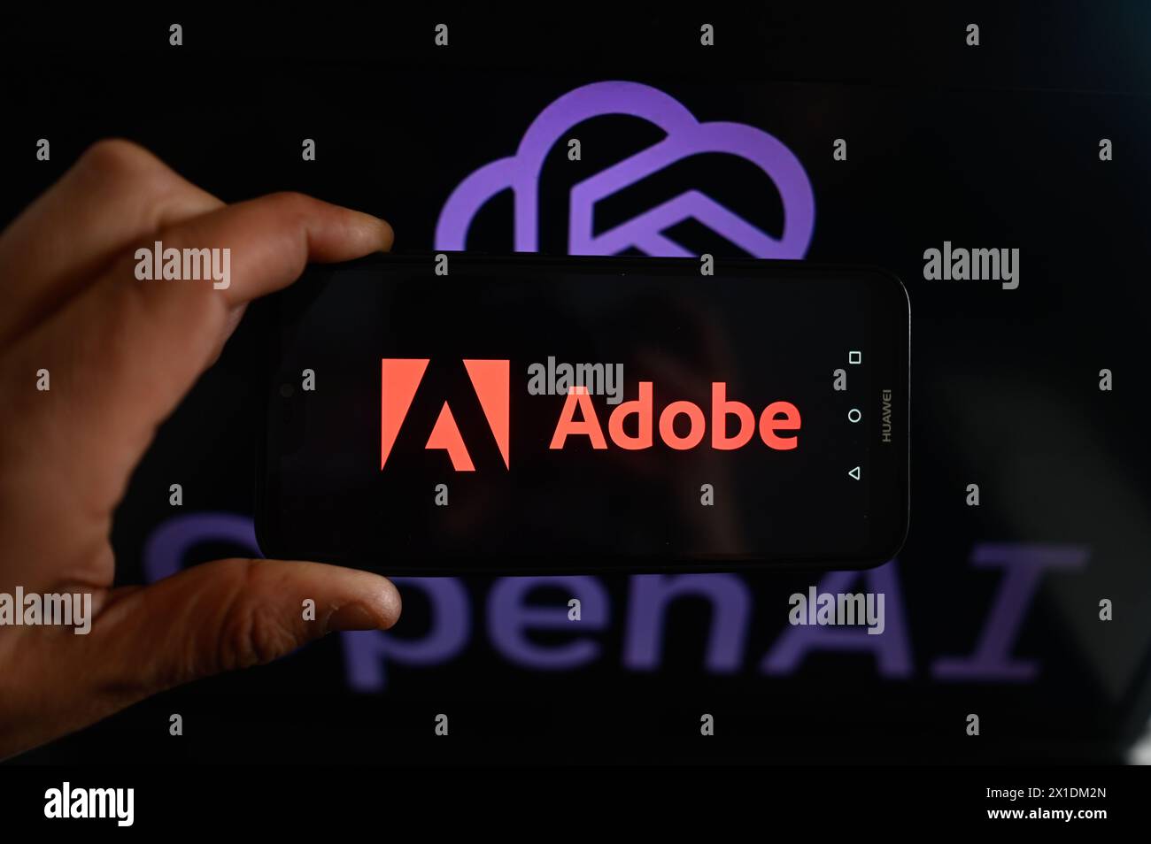 In this photo illustration, an  Adobe logo is displayed on a smartphone with an OpenAI logo in the background. Stock Photo