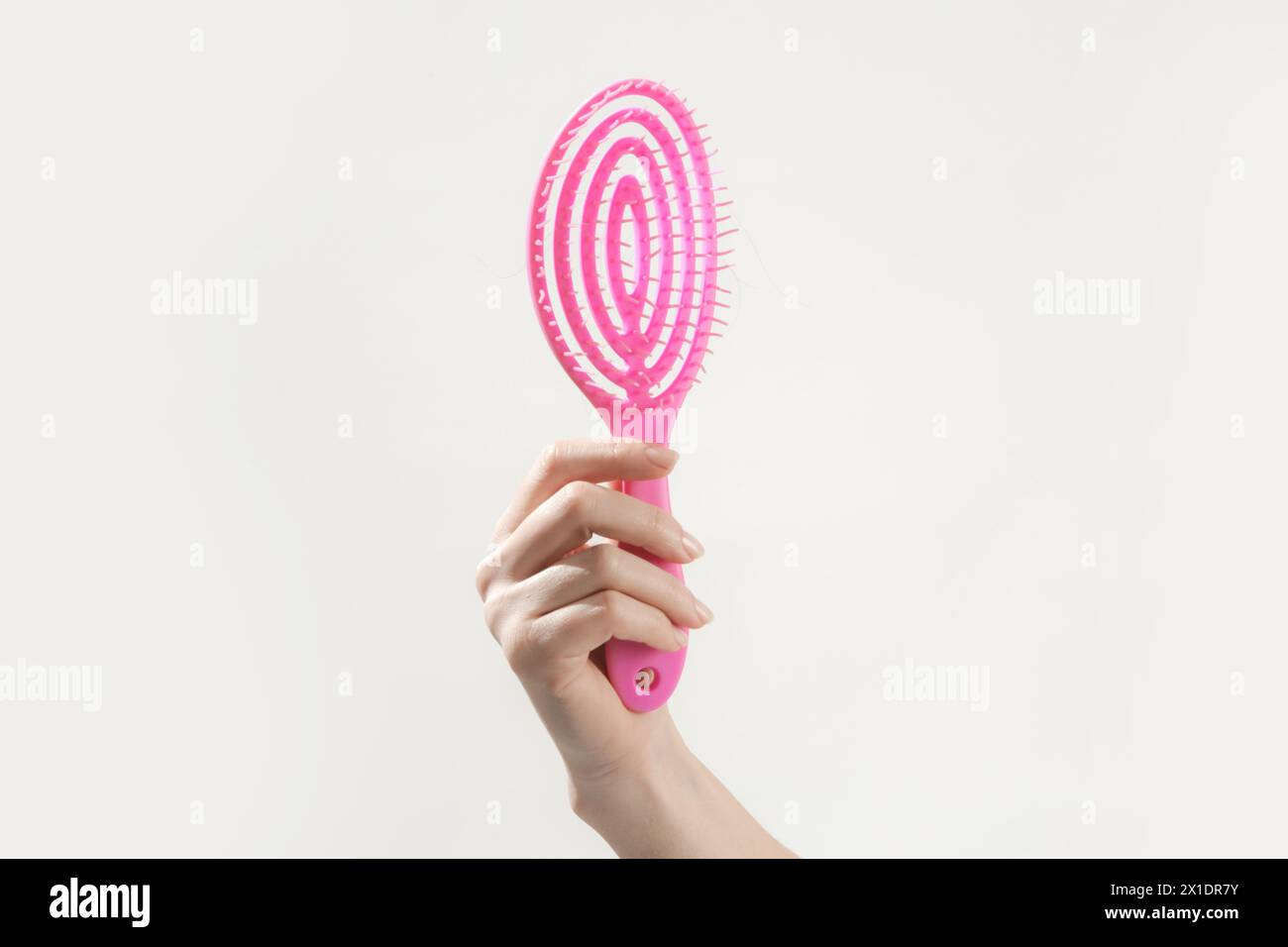 Young woman holding pink detangler hair brush, studio shot Stock Photo