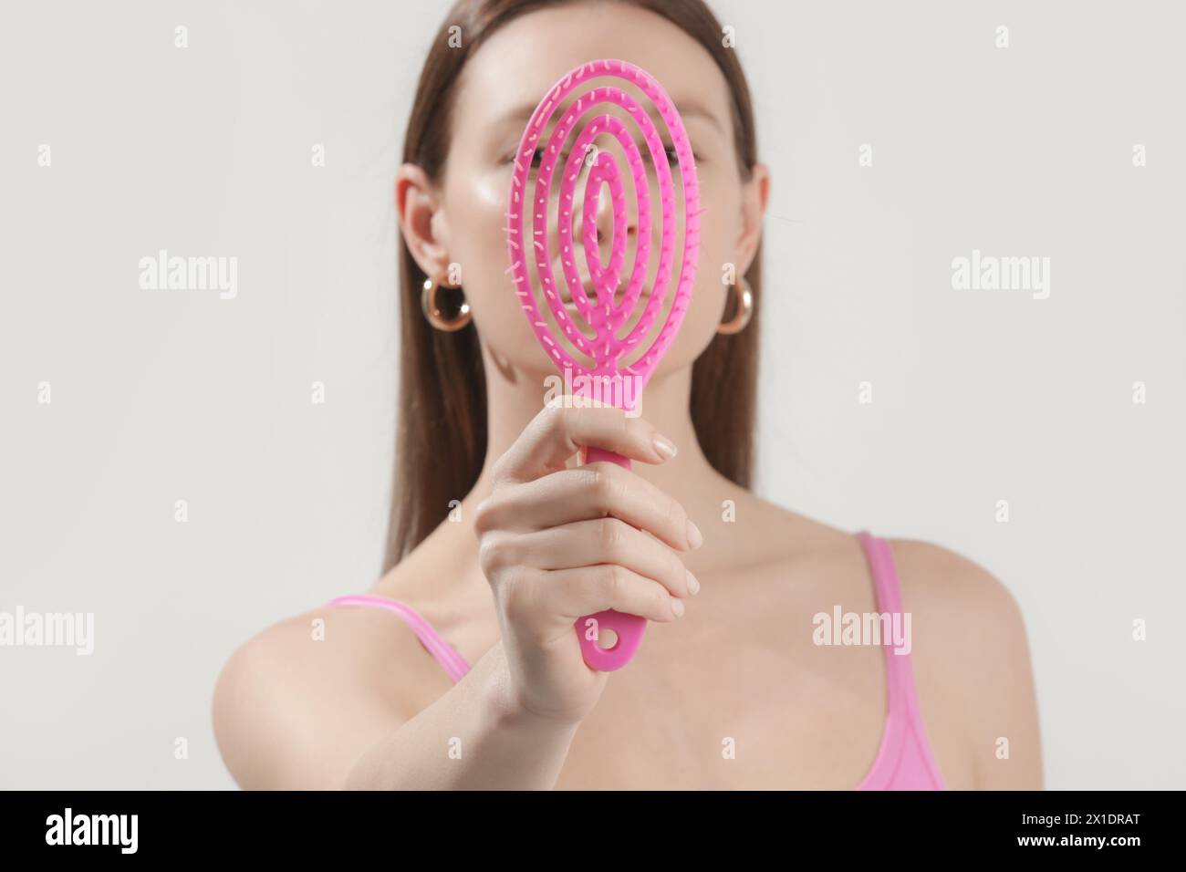 Young woman holding pink detangler hair brush, studio shot Stock Photo