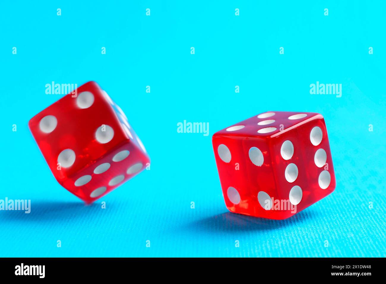 Two red game dices falling on light blue background, closeup Stock Photo
