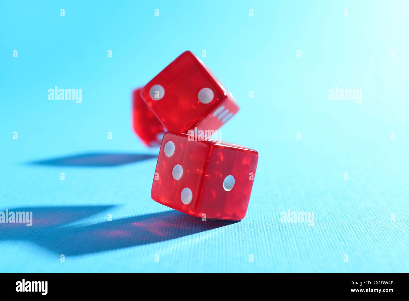 Three red game dices falling on light blue background, closeup Stock Photo