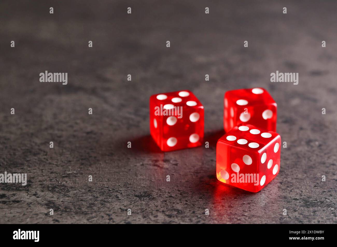 Three red game dices on grey textured table Stock Photo