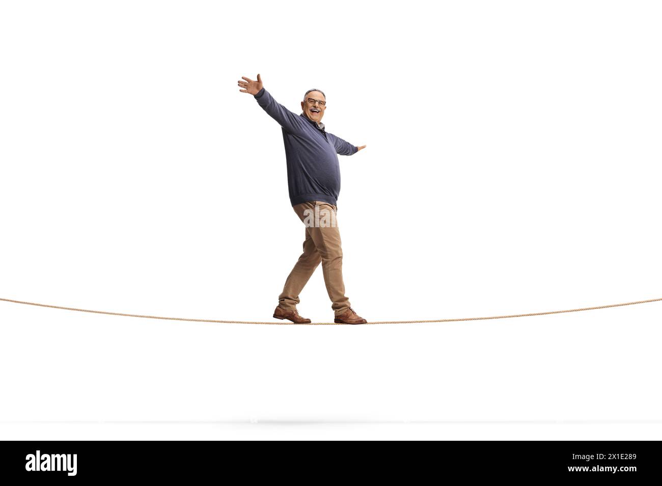Full length shot of a mature man walking on a rope isolated on white background, keep balance concept Stock Photo