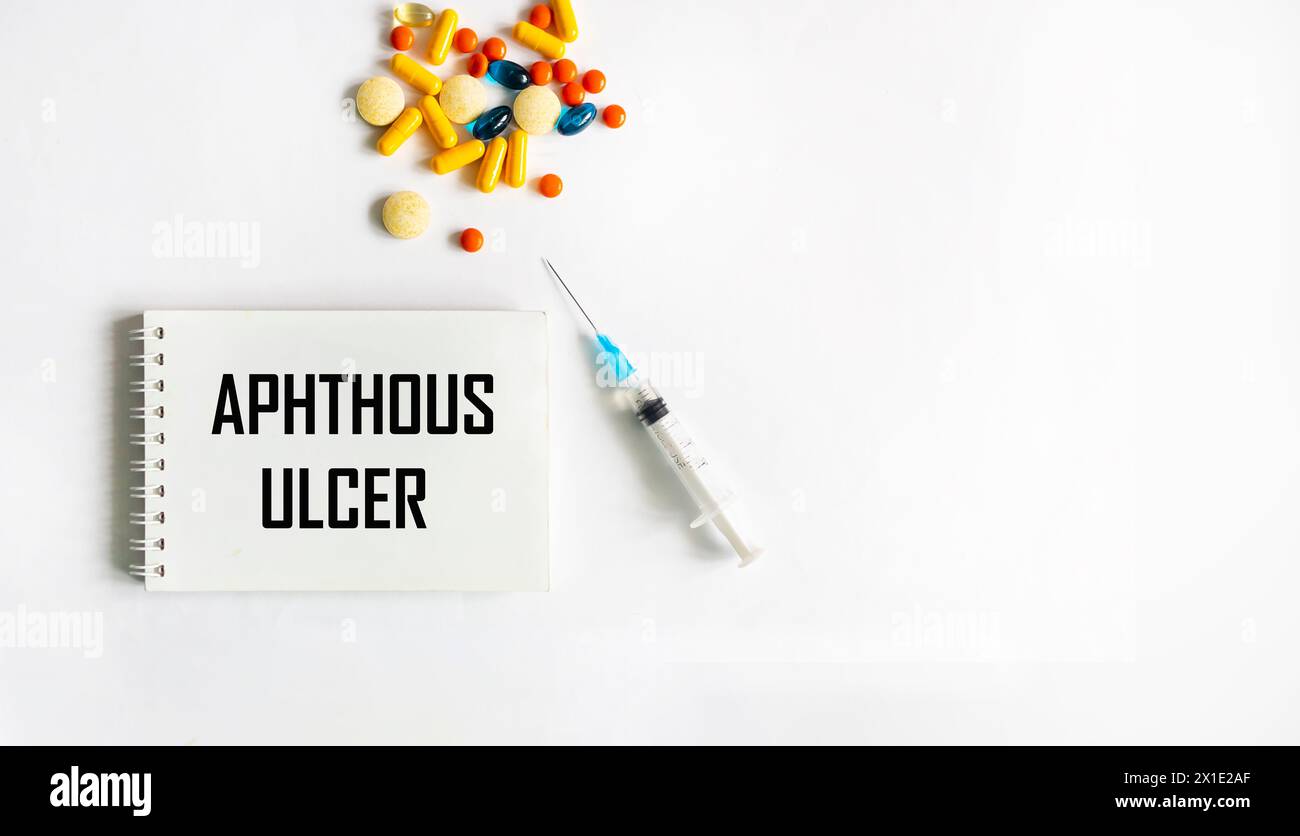 Medical term aphthous ulcer in a card on a white background with pills and an injection. Stock Photo