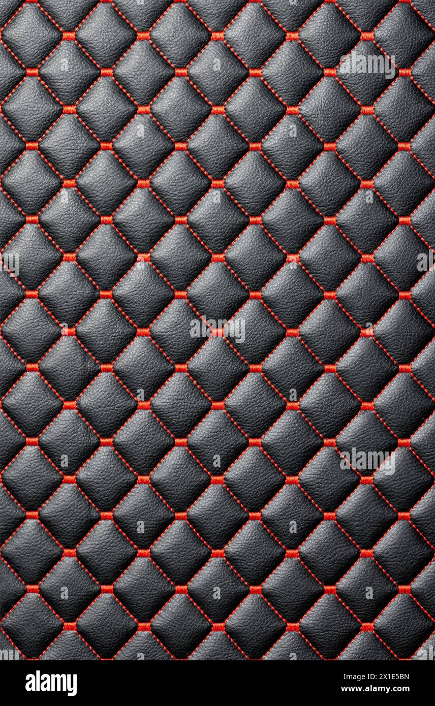 The leather background is made of stitched black leather with even red thread stitching. Vertical image. Stock Photo