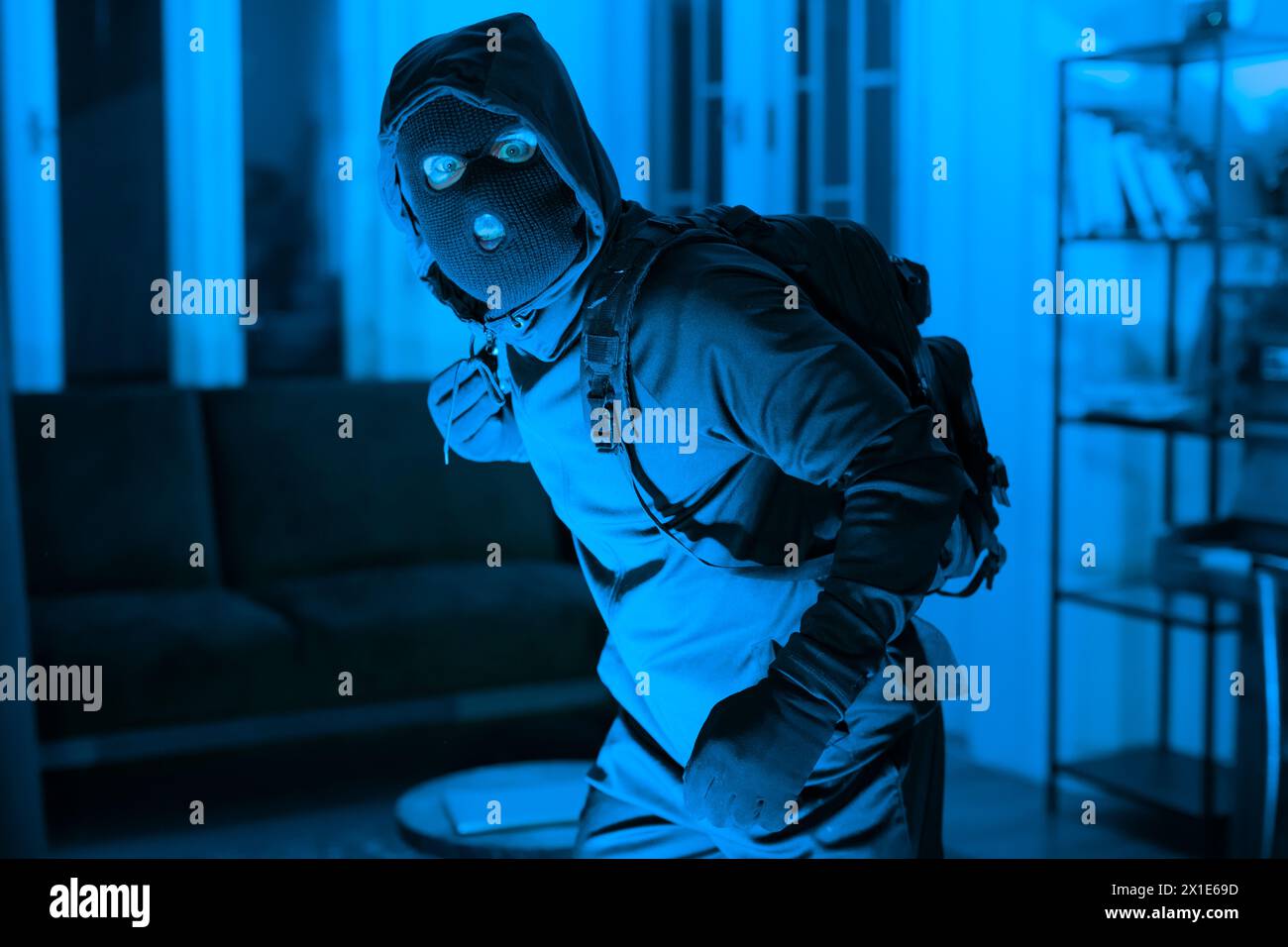 Burglar in mask sneaking inside a house Stock Photo