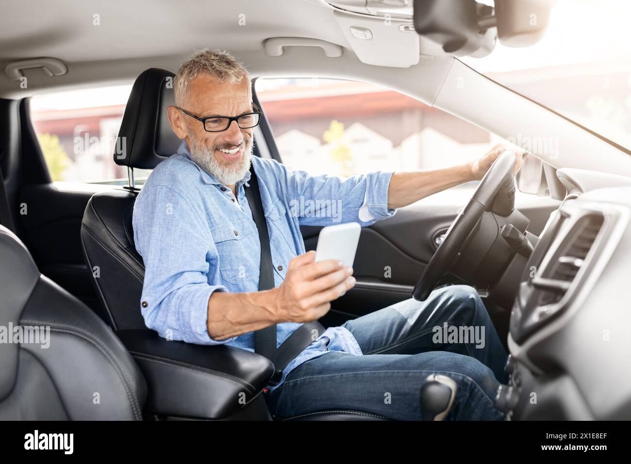 Senior man using a smartphone in the car Stock Photo