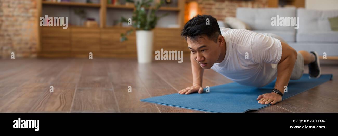 Strong asian mature man making strength workout at home Stock Photo