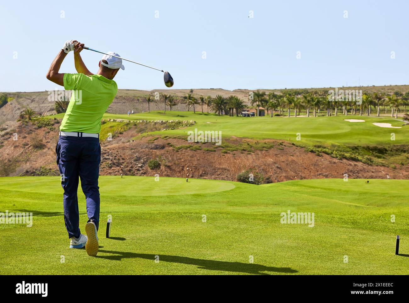 Golfer on a golf course, ready to tee off. Golfer with golf club hitting the ball for the perfect shot. Stock Photo