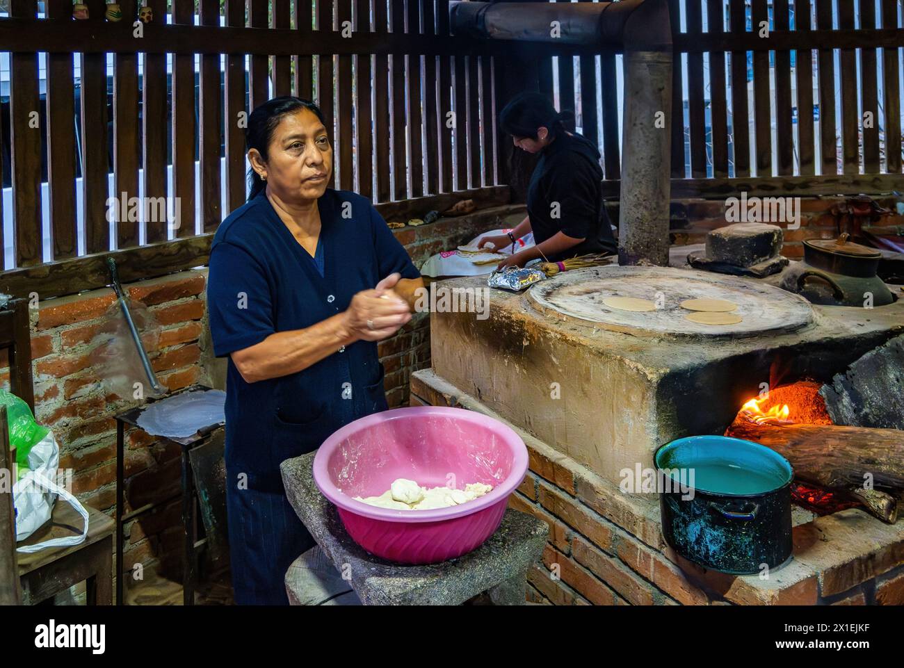 Mother and daughter cooking corn tortilla on traditional flat topped