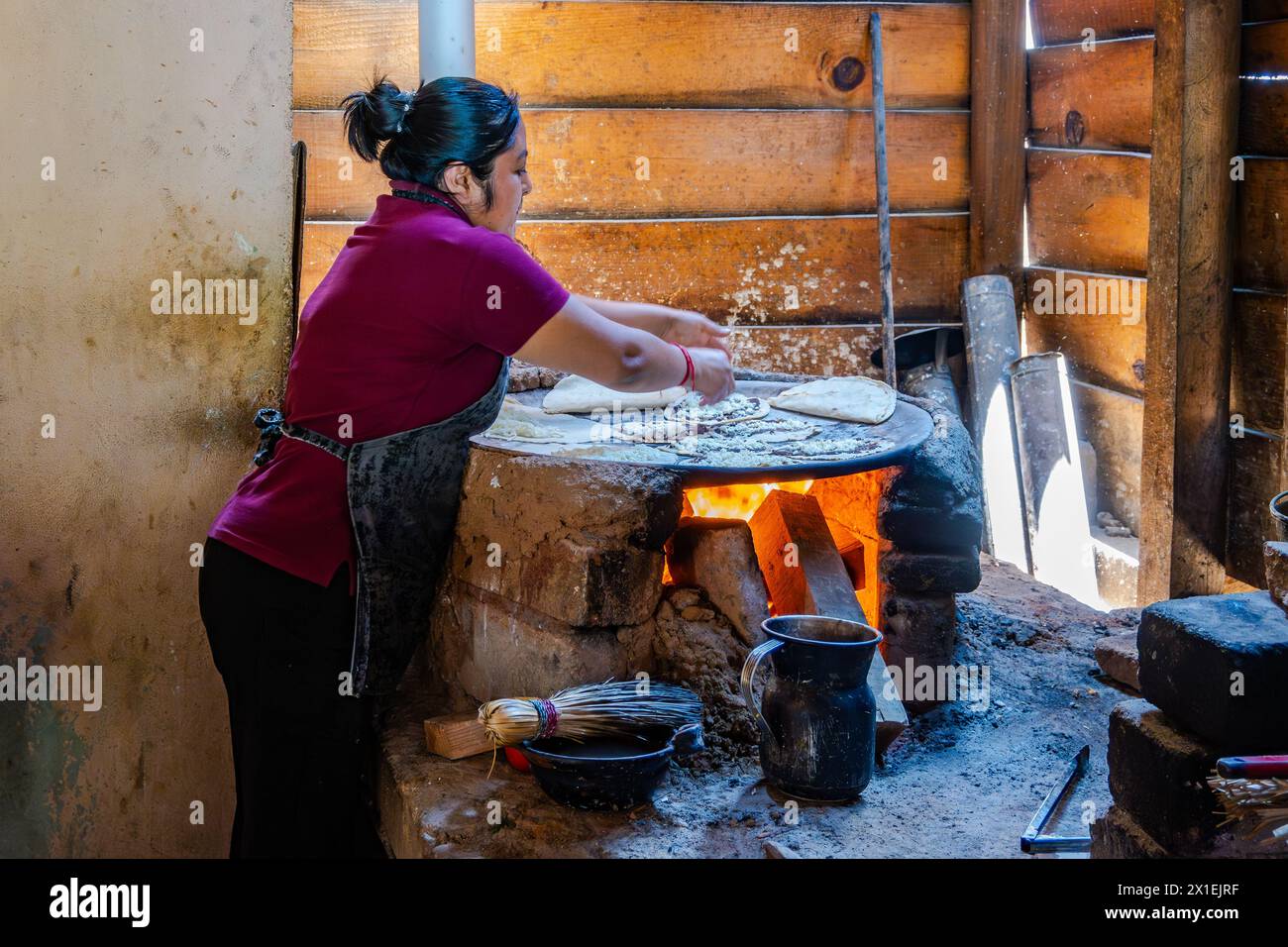 A woman cooking corn tortilla on traditional flat topped stove. Oaxaca