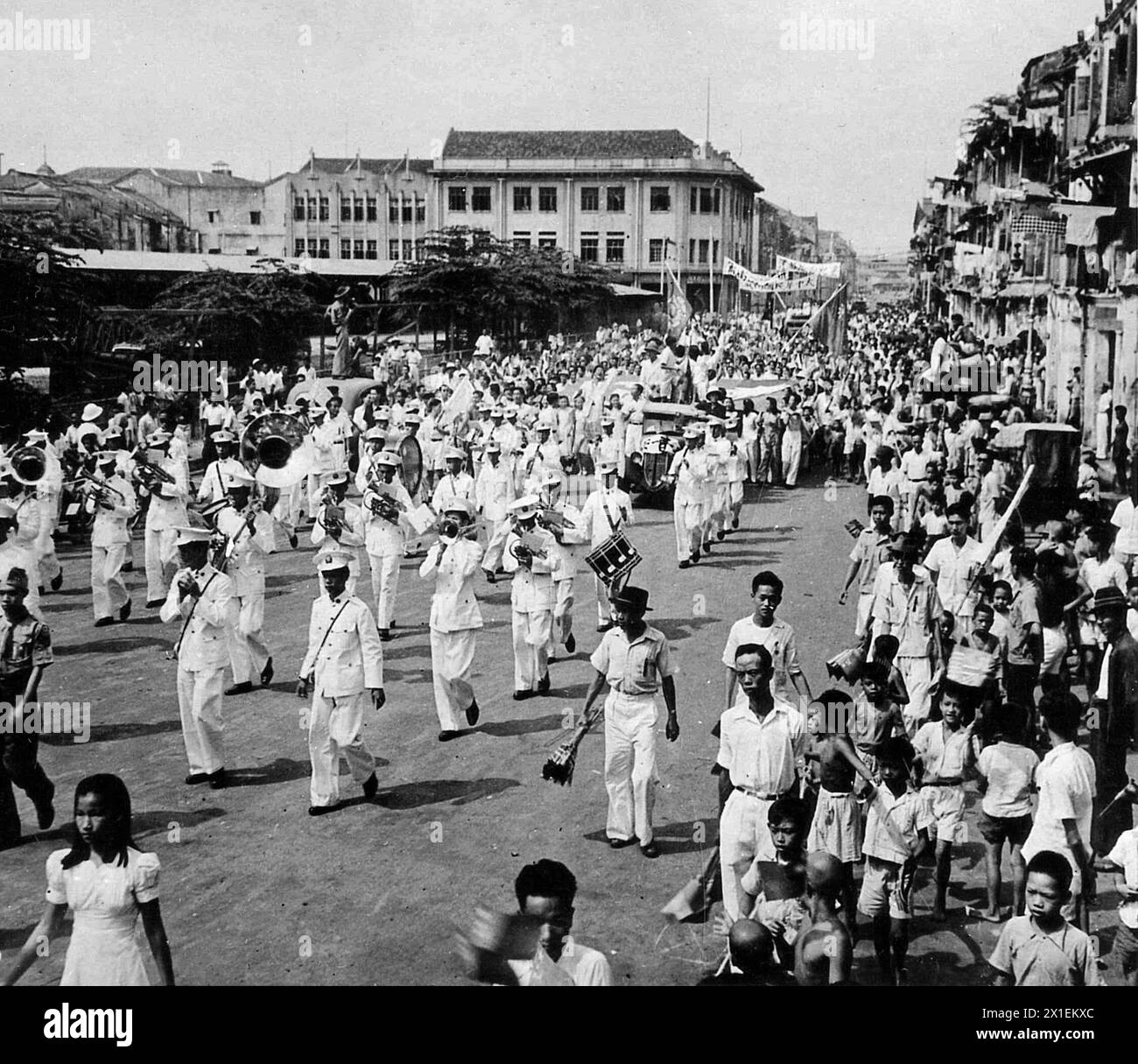 Original Caption: 'Brass band leads procession of people of Singapore in Victory Celebration, to demonstrate their rejoicing at the landing of Empire Forces to occupy Singapore after 3.5 years of Japanese rule, the people held a celebration. The band is the Royal marines.' ca. September 1945 Stock Photo