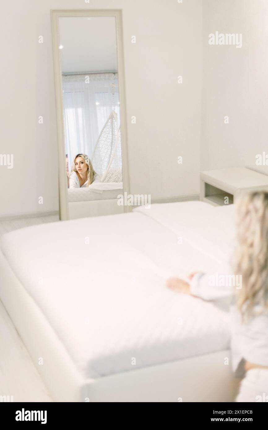A woman is holding a smartphone, taking a picture of herself reflected in a mirror. Stock Photo