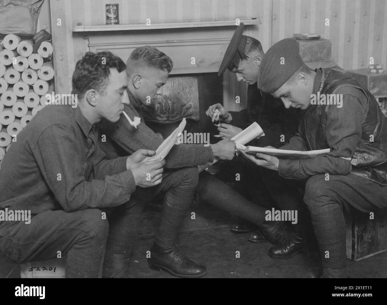 Original caption: Sailors and soldiers bacheloring in London, sitting around an open fireplace in their billet, reading and smoking ca. 1919 Stock Photo