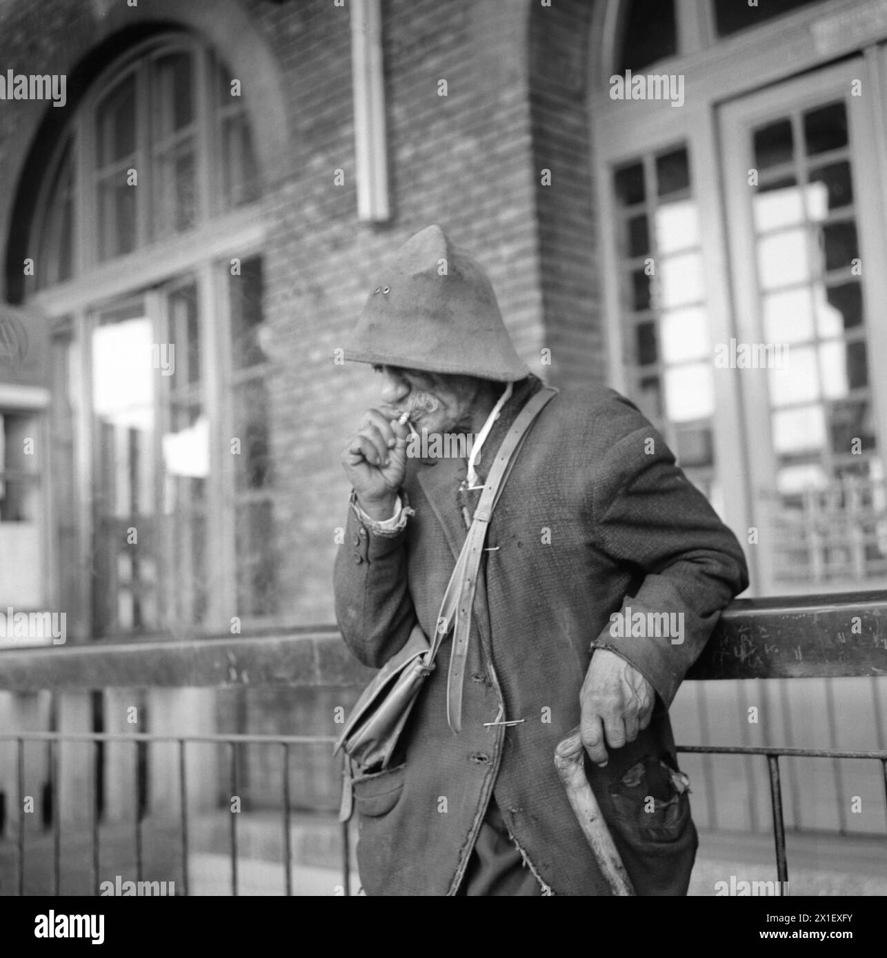 Socialist Republic of Romania in the 1970s. Homeless man outside a train station smoking a cigarette. Stock Photo
