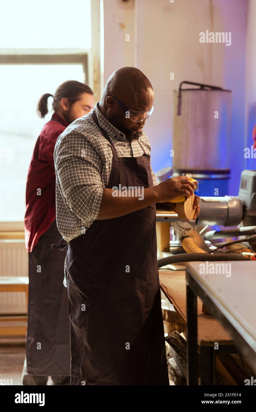 African american artisan in studio using sandpaper for smoothing wooden