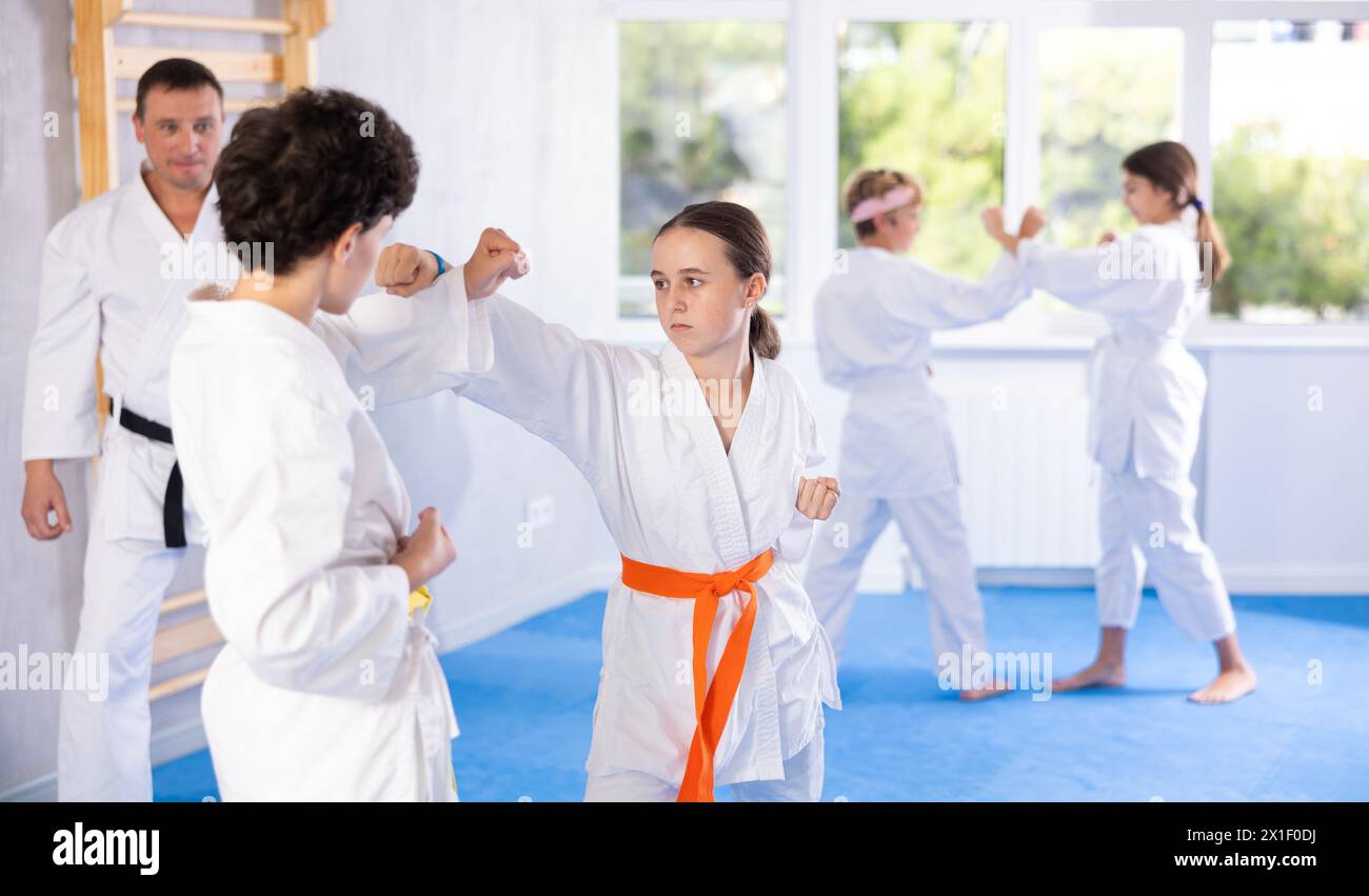 Teenagers Girl And Boy In Kimono Sparring Together In Gym During Karate teenagers-girl-and-boy-in-kimono-sparring-together-in-gym-during-karate